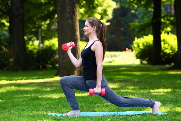 Outdoor Fitness: Lunges with Dumbbells in a Scenic Park